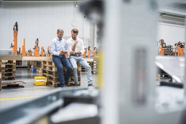 Two men sharing tablet on factory shop floor - DIGF10618