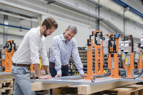 Two men looking at tablet on factory shop floor stock photo