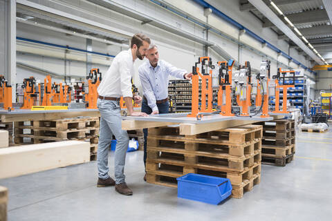 Two men talking on factory shop floor stock photo