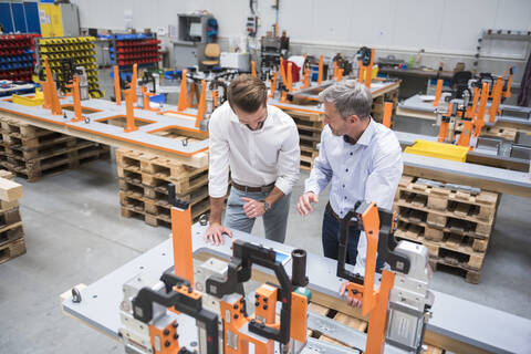 Two men talking on factory shop floor stock photo