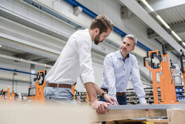 Zwei Männer unterhalten sich in einer Fabrikhalle - DIGF10625