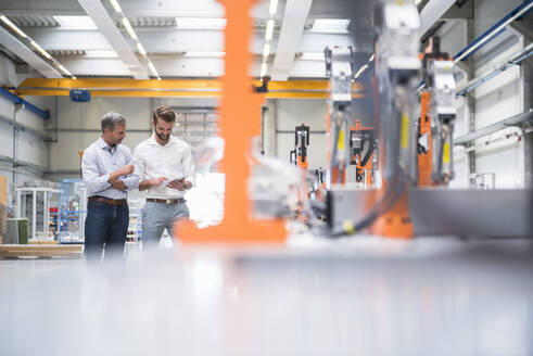 Two men sharing tablet on factory shop floor - DIGF10626