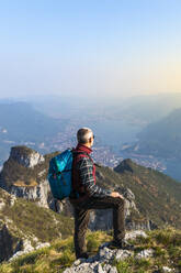 Rear view of hiker on mountaintop, Orobie Alps, Lecco, Italy - MCVF00304