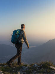 Pensive hiker using smart phone on mountain peak during sunrise at  Bergamasque Alps, Italy stock photo