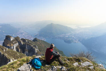 Rear view of hiker sitting on mountaintop, Orobie Alps, Lecco, Italy - MCVF00315