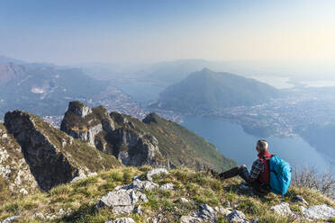 Rückansicht eines Wanderers, der auf einem Berggipfel sitzt, Orobie Alpen, Lecco, Italien - MCVF00319