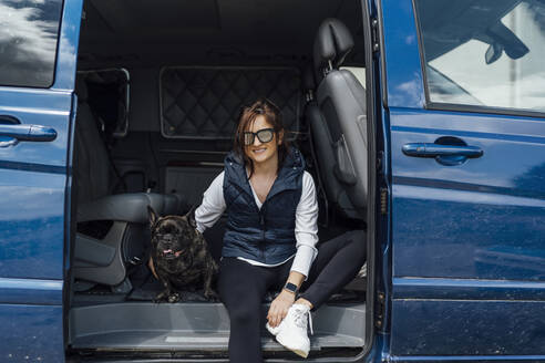 Porträt einer lächelnden Frau, die mit ihrer Bulldogge in einem Lieferwagen sitzt - OCMF01207