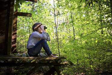 Girl using binoculars in forest - LVF08873