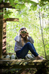 Portrait of girl using binoculars in forest - LVF08874