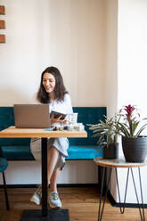 Portrait of smiling young woman working at home office - DAWF01438