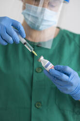 Woman in protective wear preparing covid-19 vaccination - SNF00124