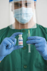 Man in protective wear holding covid-19 vaccine and syringe - SNF00133