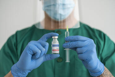 Man in protective wear holding covid-19 vaccine and syringe - SNF00134