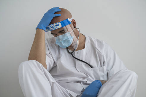 Exhausted man in protective wear sitting on the floor - SNF00144