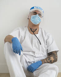 Exhausted man in protective wear sitting on the floor - SNF00145