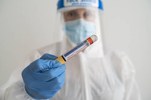 Woman in protective wear holding negative covid-19 test - SNF00150