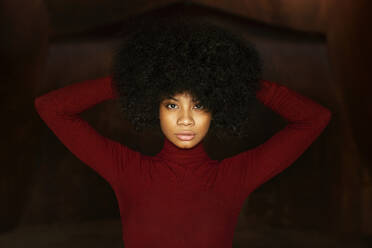 Portrait of young woman in red bodysuit, hands in hair - TCEF00632
