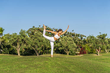 Woman doing yoga on lawn in sunshine - DLTSF00661