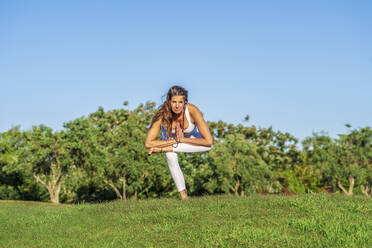 Portrait of woman doing yoga on lawn in sunshine - DLTSF00669