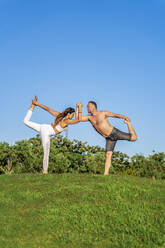 Mature couple doing yoga on lawn in sunshine together - DLTSF00673
