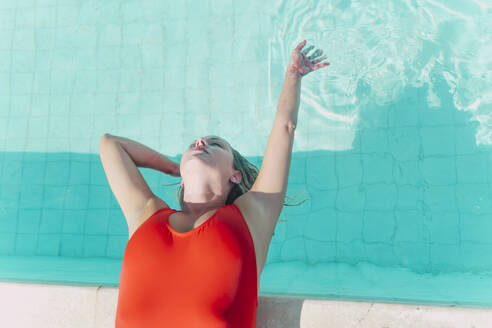 Frau im roten Badeanzug am Pool liegend - ERRF03663