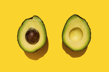 Studio shot of halved avocado on yellow background - GEMF03701