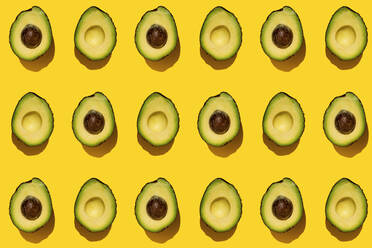 Pattern of halved avocados on yellow background - GEMF03702