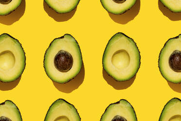 Muster von halbierten Avocados auf gelbem Hintergrund - GEMF03703