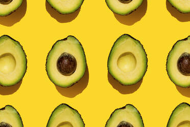 Pattern of halved avocados on yellow background - GEMF03703