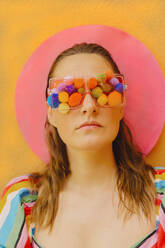 Porträt einer Frau mit Brille und bunten Pompons, die ihre Augen bedecken - ERRF03674