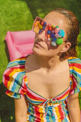 Portrait of woman wearing glasses with colourful pom poms - ERRF03698