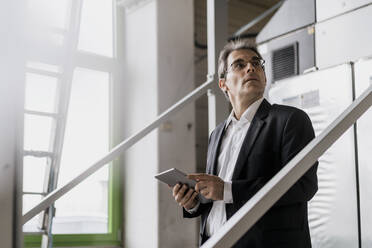 Mature businessman holding tablet in a factory - DIGF10651