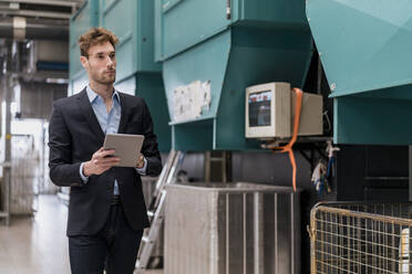 Young businessman holding tablet in a factory - DIGF10664