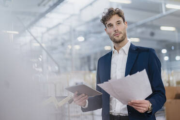 Young businessman with documents and tablet in a factory - DIGF10698