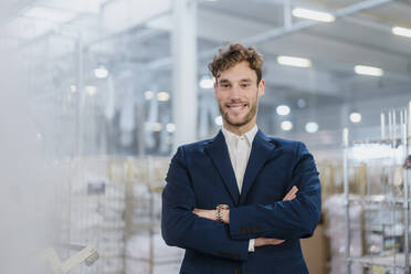 Portrait of a smiling young businessman in a factory - DIGF10699