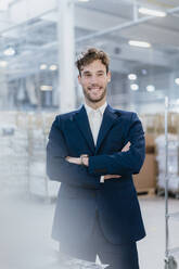 Portrait of a smiling young businessman in a factory - DIGF10700