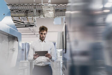 Young businessman using tablet in a factory - DIGF10714