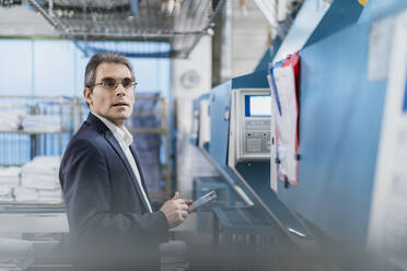 Mature businessman holding tablet in a factory - DIGF10731