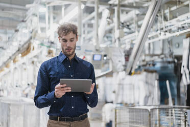 Young businessman using tablet in a factory - DIGF10738