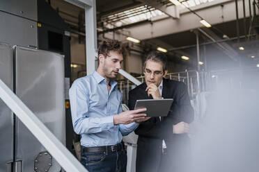 Two businessmen with tablet having a meeting in a factory - DIGF10744