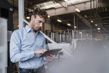 Young businessman using tablet in a factory - DIGF10745