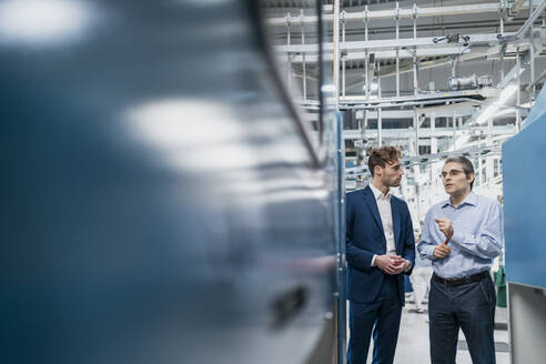 Zwei Geschäftsleute bei einem Treffen in einer Fabrik - DIGF10748