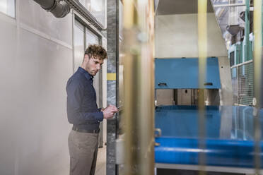 Mature businessman with tablet at conveyor belt in a factory - DIGF10764