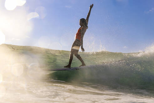 Weibliche Surferin balanciert auf Surfbrett - KNTF04600