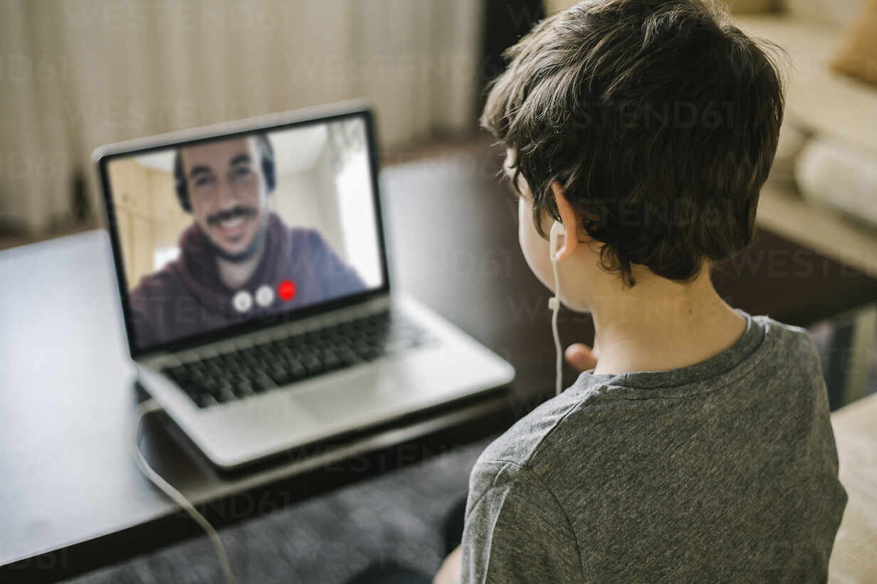 Young boy using a laptop for video chat with his father stock photo