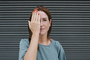 Woman covering one eye with her hand - XLGF00160