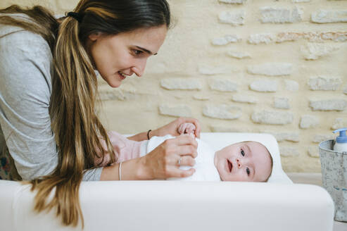 Mutter schaut auf ihr Baby auf dem Wickeltisch - KIJF03009