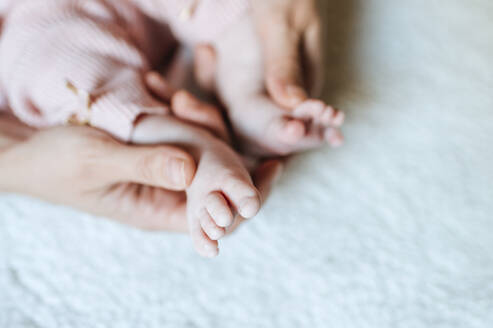 Nahaufnahme von Babyfüßen, die von der Hand der Mutter gehalten werden - KIJF03014
