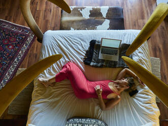 Frau entspannt sich auf dem Bett im Hotelzimmer - VEGF02152