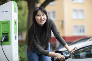 Carsharing, Frau beim Aufladen eines Elektroautos - SGF02631